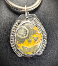 Load image into Gallery viewer, An oval-shaped Bumblebee Jasper sterling silver pendant with a unique circular pattern, featuring a yellow-orange and black stone set in a silver frame on a black background.